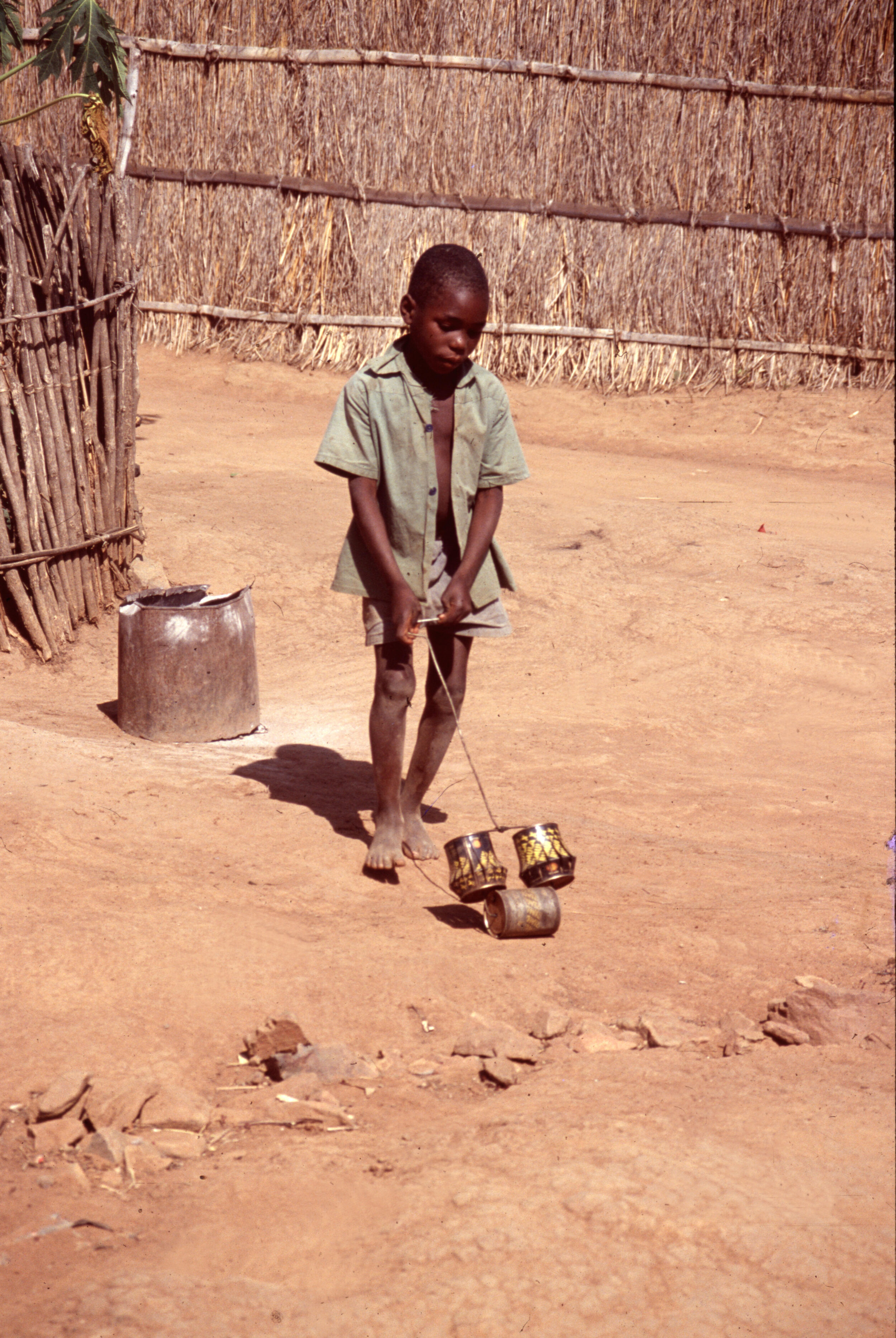 Kind in Simbabwe mit gebastelter Straßenwalze aus Blechdosen