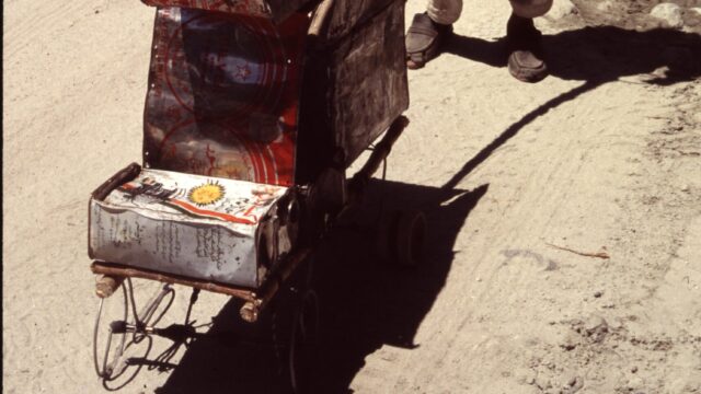 Kind in Pakistan am Karakorum-Highway mit handgemachtem Transportfahrzeug